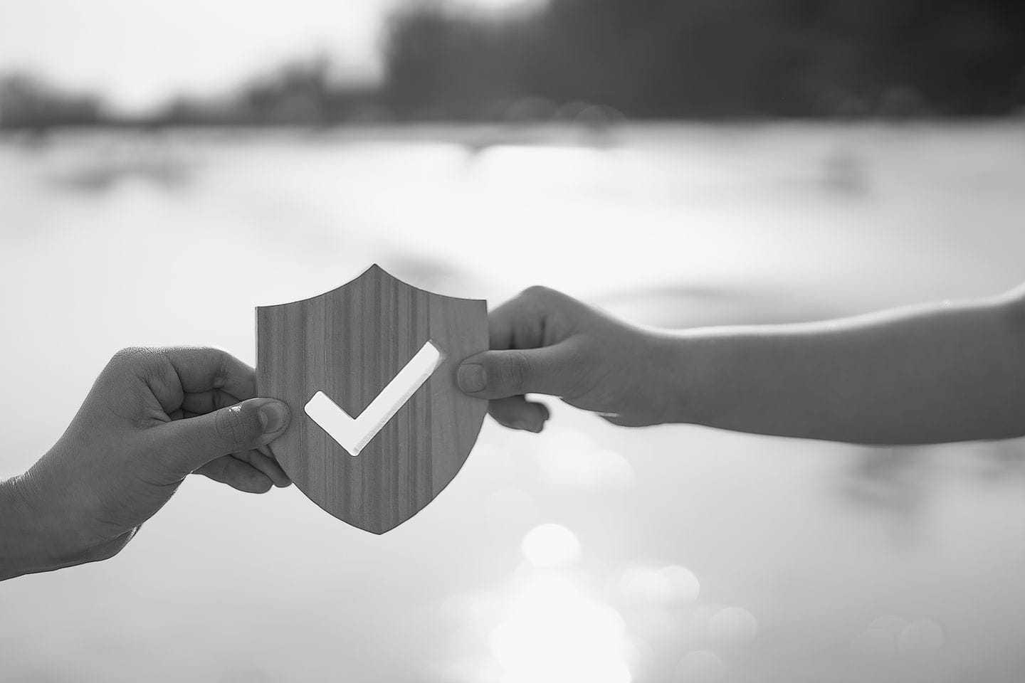 Deux mains assemblant un puzzle avec un bouclier et une coche, symbolisant la garantie et la protection